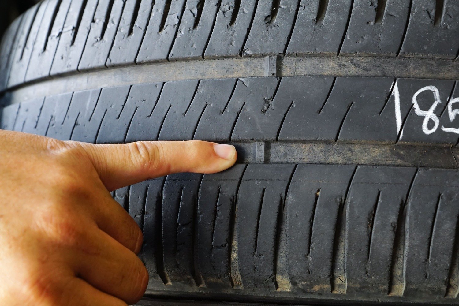 finer pointing to location of car tire tread wear indicator